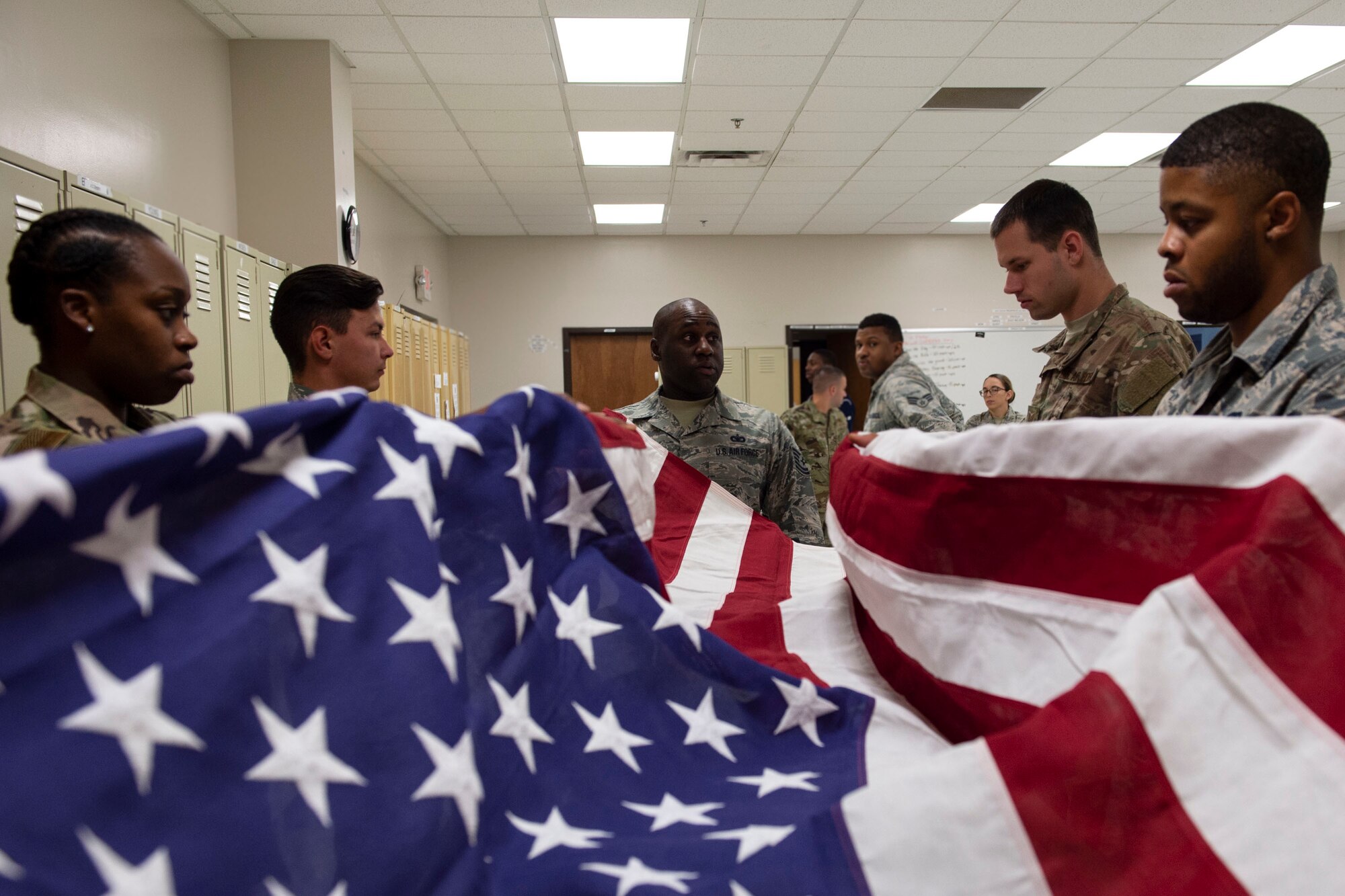 Tech. Sgt. Jamaal Smalls, right, NCO in charge of Honor Guard, critiques six-person flag-fold training, July 25, 2019, at Moody Air Force Base, Ga. Prior to being a part of Moody’s Honor Guard, Smalls was a master military training instructor. (U.S. Air Force photo by Airman Azaria E. Foster)