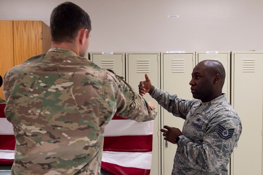 Tech. Sgt. Jamaal Smalls, right, NCO in charge of Honor Guard, provides instruction on how to fold the flag during six-person flag-fold training, July 25, 2019, at Moody Air Force Base, Ga. Smalls’ experience as a master military training instructor helped him develop his professionalism and attention to detail that he now uses in Honor Guard. (U.S. Air Force photo by Airman Azaria E. Foster)
