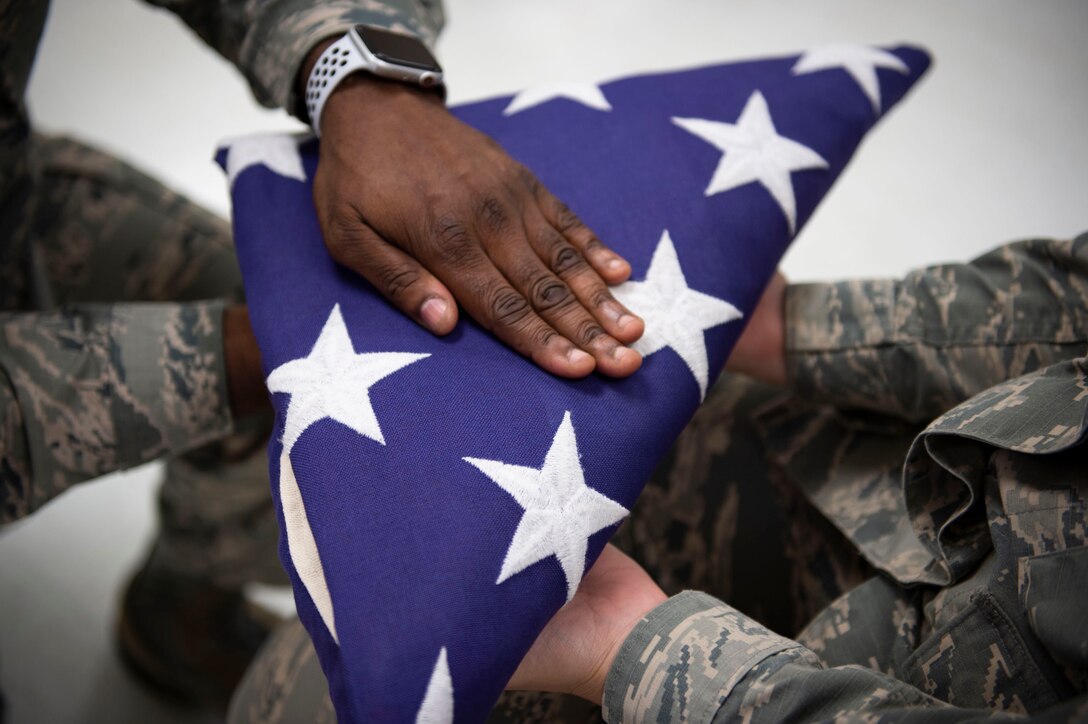 Tech. Sgt. Jamaal Smalls, NCO in charge of Honor Guard, presents the flag during six-person flag-fold training, July 25, 2019, at Moody Air Force Base, Ga. Smalls’ experience as a master military training instructor helped him develop his professionalism and attention to detail that he now uses in Honor Guard. (U.S. Air Force photo by Airman Azaria E. Foster)