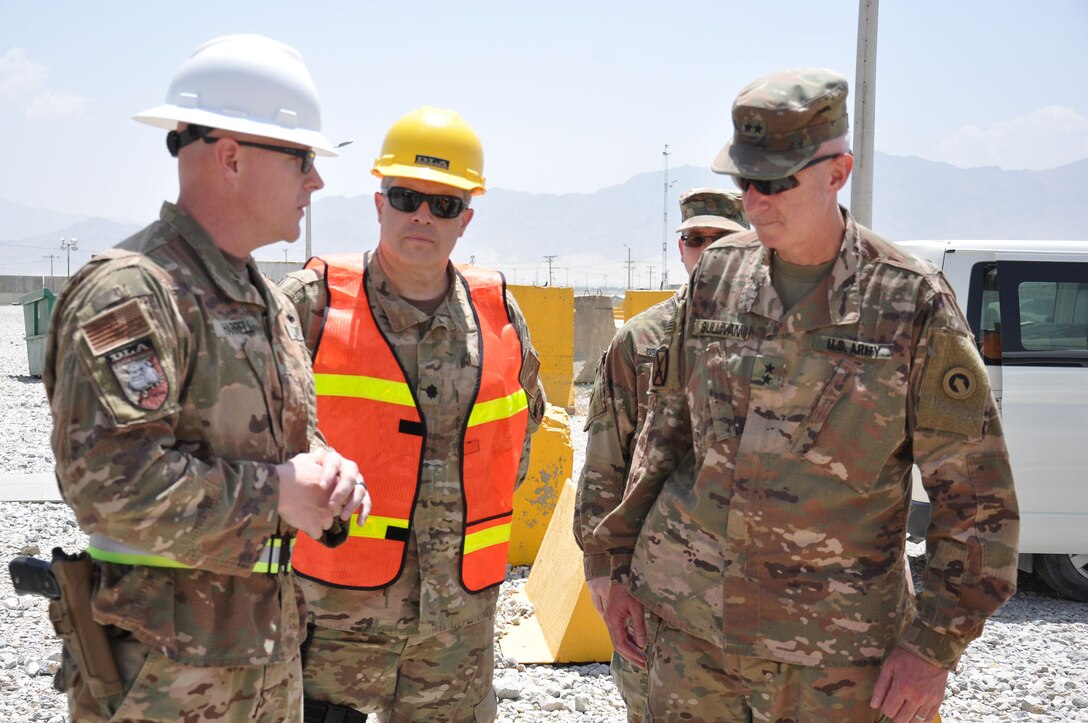 Navy Cmdr. Robert Kurkjian (center), commander of the DLA Support Team – Afghanistan, listens as Navy Lt. Cmdr. Steve Harrell, officer in in charge of DLA Disposition Services-Afghanistan; briefs Army Maj. Gen. John Sullivan, new commander of the 1st Theater Sustainment Command.