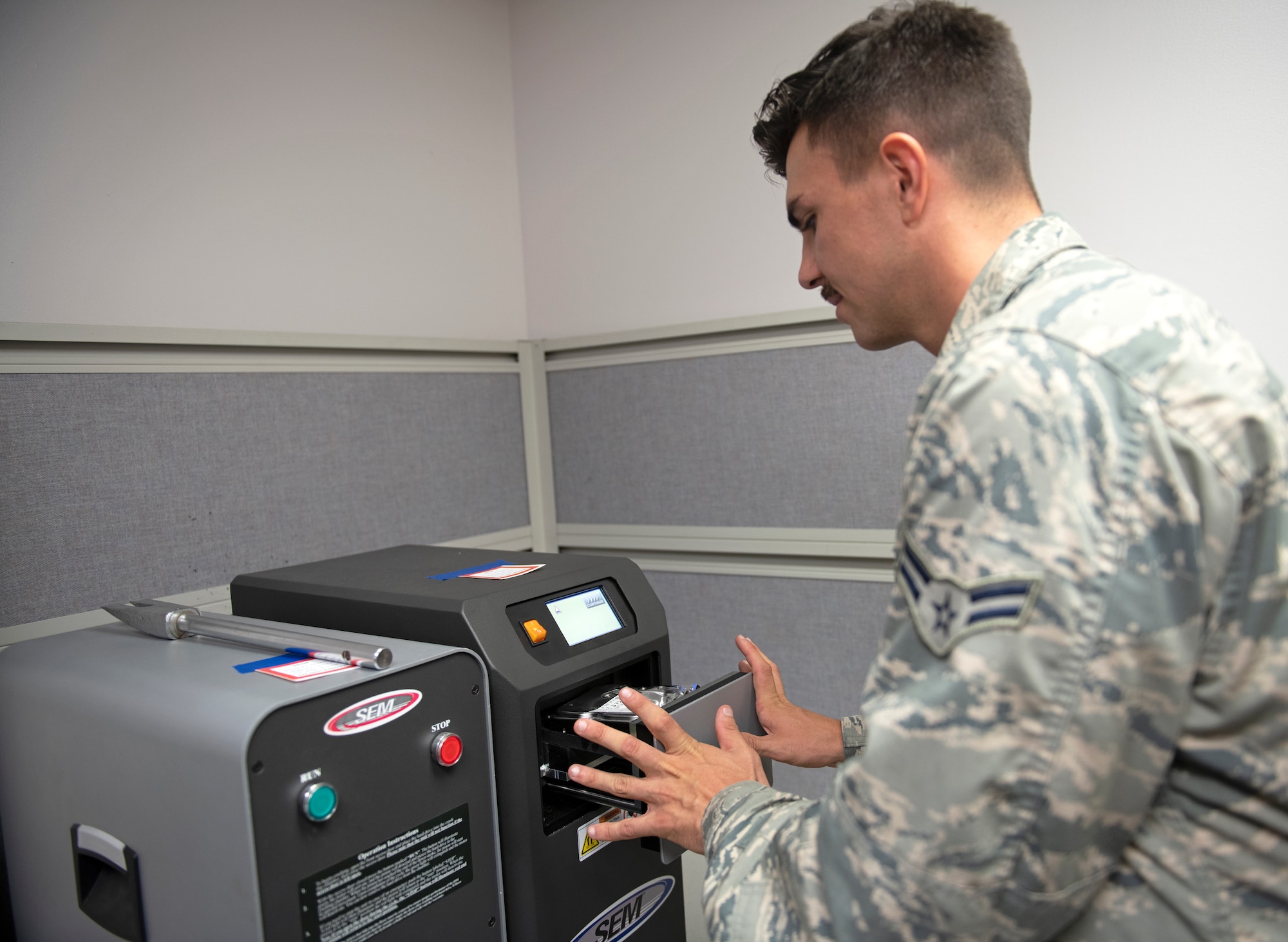 Airman 1st Class Stephen Lowe, 56th Communications Squadron cyber security technician, places a hard drive into a degausser July 31, 2019, at Luke Air Force Base, Ariz.