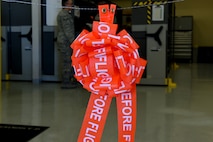 A bow made from "remove from flight" ribbons hangs on a ceremonial wire at Creech Air Force Base, Nevada, July 29, 2019. When the Tiger Aircraft Maintenance Unit support section closed in October, they merged with the Reaper AMU. (U.S. Air Force photo by Airman 1st Class William Rio Rosado)