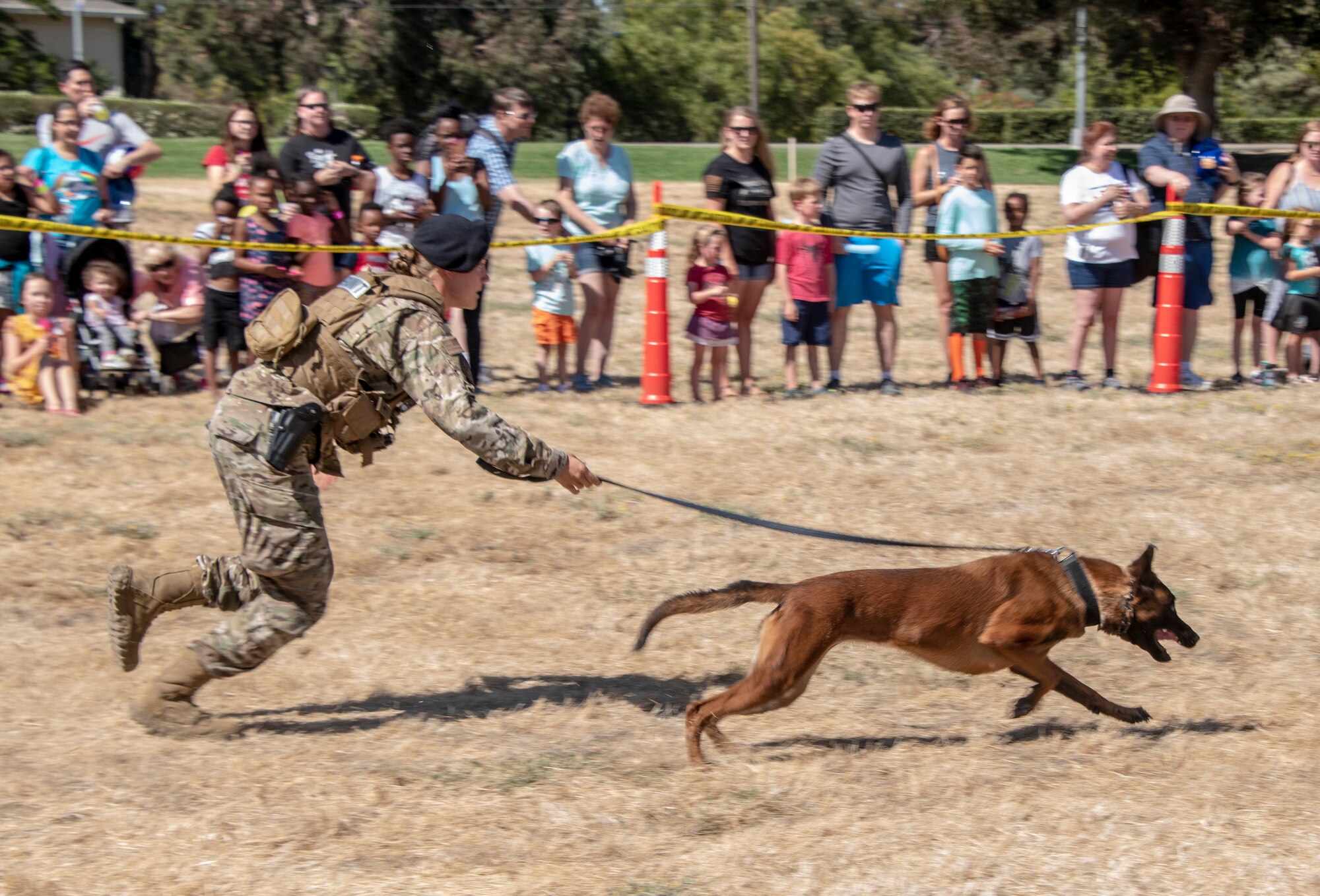 U.S. Air Force Senior Airman Alexa Ammerman, 60th Security Forces Squadron military working dog handler, runs with MWD Aaraphao, during the 60th SFS National Night Out Aug. 6, 2019, at Travis Air Force Base, California. National Night Out is an annual community-building campaign that promotes police-community partnerships and neighborhood camaraderie. The event included a demonstration by military working dogs, live music and a variety of activities for children. (U.S. Air Force photo by Heide Couch)