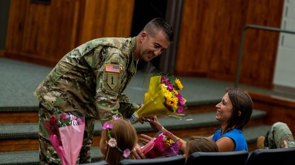 Chief Warrant Officer 4 Ryan Little,  of Pleasant Plains, Illinois, presents flowers to wife Jade, and daughters Molly and Kate, during his promotion ceremony at Camp Lincoln, Springfield, Illinois, August 7, 2019. Chief Warrant Officer 4 Little serves as the Senior Maintenance Officer, Joint Force Headquarters, Illinois National Guard.