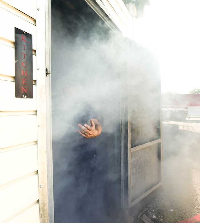 Corey Garritsen, 11th Civil Engineer Squadron Fire Department inspector, reaches a hand out to invite others to watch the cadets navigate a smoke filled room on Joint Base Andrews, Md., July 27, 2019. Smoke machines filled the rooms making it hard to see without proper gear.