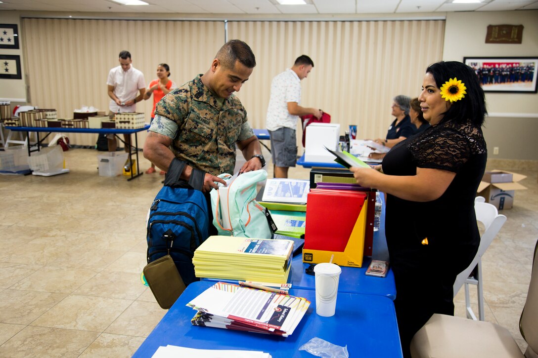 First Sergeant Enrique De Anda, MCLB Barstow HQ Co first sergeant, picks up school supplies for the young students in his extended family from volunteer Janet Rocha-Diaz at the Back To School Brigade annual school supply giveaway, Aug. 1, at the Maj. Gen. James L. Day Conference Center aboard the base.