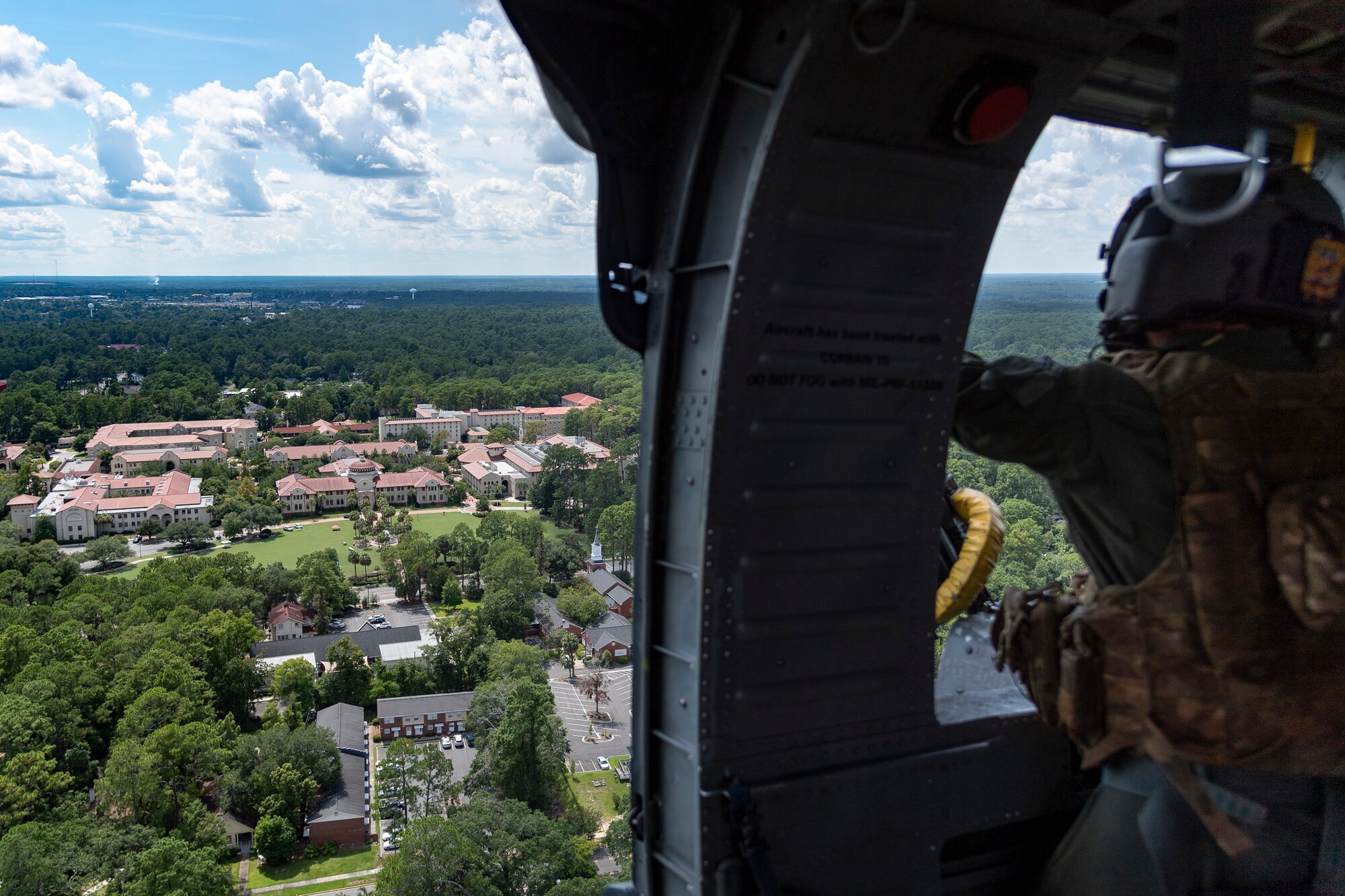 An Airman assigned to the 41st Rescue Squadron (RQS) looks out of an HH-60G Pave Hawk over Valdosta State University (VSU) before National Night Out Aug. 6, 2019, in Valdosta, Ga. National Night Out is an annual event that promotes relationships between police and the community in an effort to prevent crime. Representatives from Team Moody participated to create local community awareness and build support for the Air Force mission. (U.S. Air Force photo by Airman 1st Class Hayden Legg)