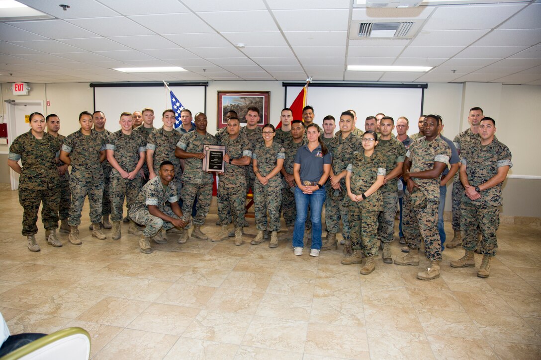 Members of Headquarters Company, Marine Corps Logistics Base Barstow, Calif., gather around company commander Maj. Ernest Robinson as he displays the plaque detailing the Voluntary Protection Program's Installation Safety Achievement Award. The plaque was presented to all departments aboard base for their part in making possible the award for installation safety and the Individual Safety Achievement award for a Special Government Employee. The plaque was presented during the Quarterly Awards breakfast held at the Maj. Gen. James l. Day Conference Center aboard base Aug. 6.
