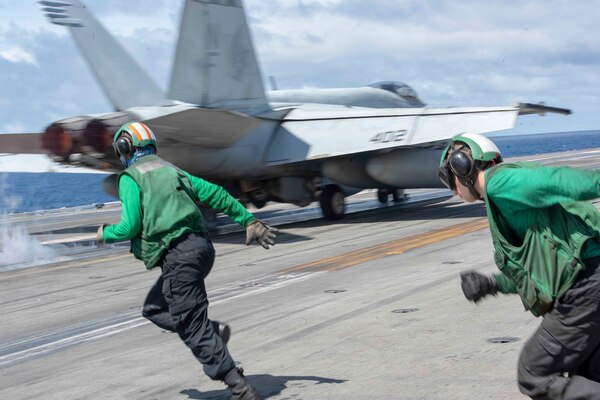 Sailors run on an aircraft carrier