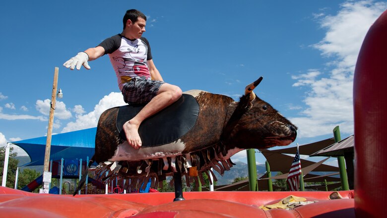 Micheal Murphy rides a mechanical bull during the annual Salute Picnic at Hill Air Force Base, Utah, Aug. 2, 2019. This was the 19th year the Top of Utah Military Affairs Committee sponsored the event for Hill's military and family members. The first event was held December 2001 as a welcome home celebration for military deployed following 9/11. (U.S. Air Force photo by R. Nial Bradshaw)