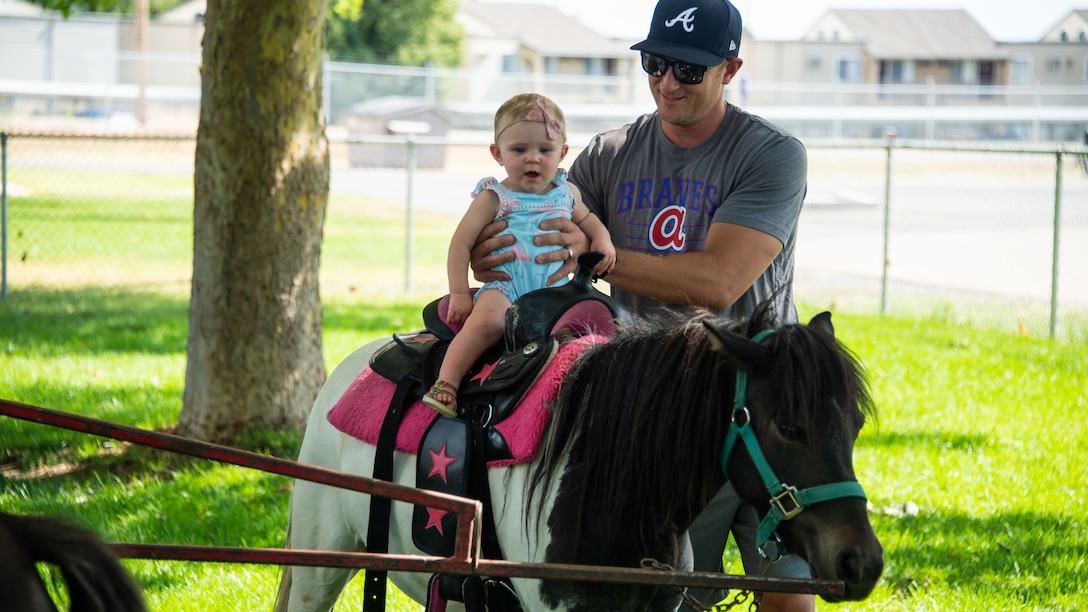 Josie rides a pony carousel with her father John Hazel during the annual Salute Picnic at Hill Air Force Base, Utah, Aug. 2, 2019. This was the 19th year the Top of Utah Military Affairs Committee  sponsored the event for Hill's military and family members. The first event was held December 2001 as a welcome home celebration for military deployed following 9/11. (U.S. Air Force photo by R. Nial Bradshaw)