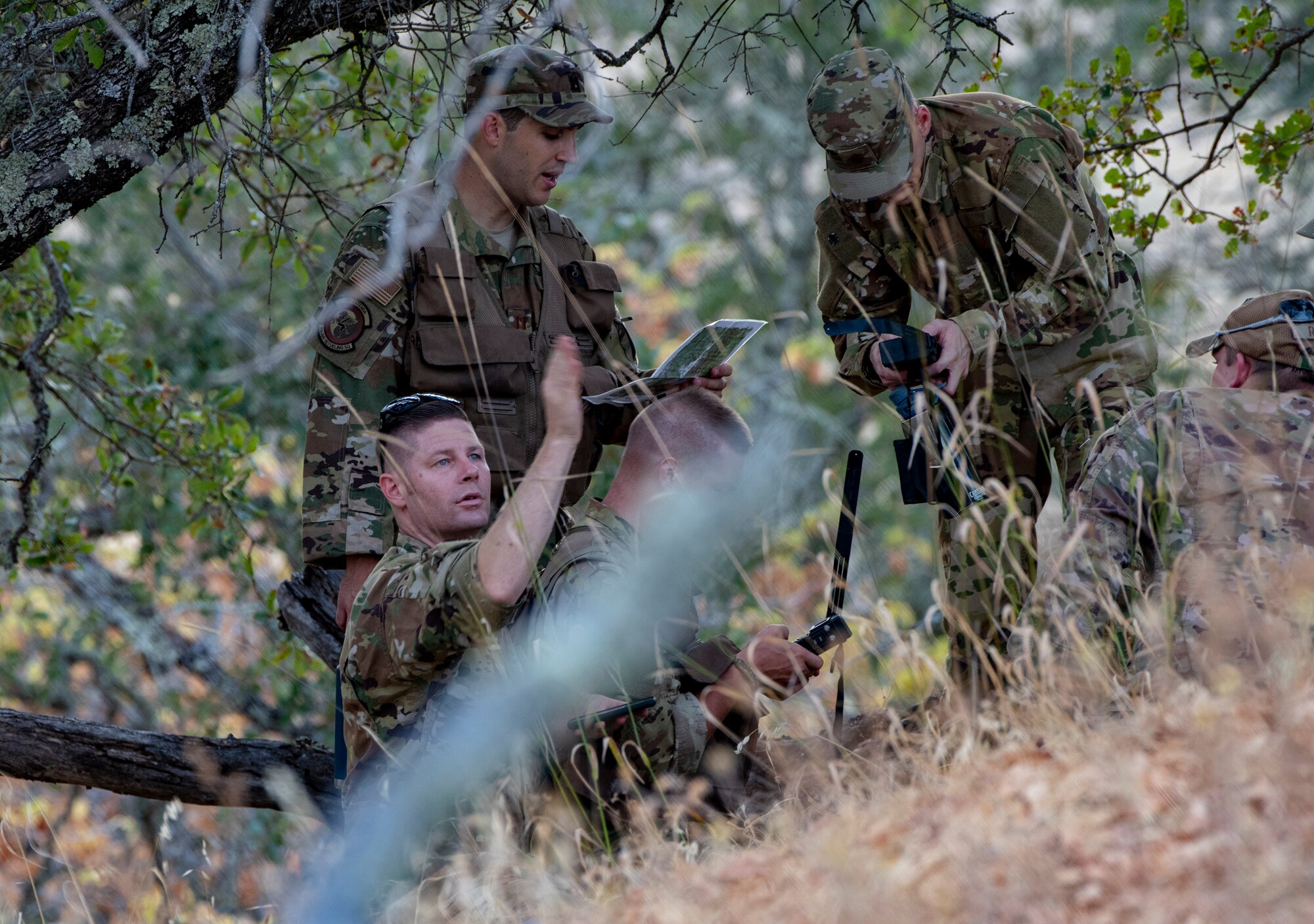Aircrew members use communication devices and other supplies during a Survival, Evasion, Resistance and Escape training exercise that will last well into the evening, Aug. 5, 2019 in a remote area near Travis Air Force Base, California. SERE instructors conduct the training to improve aircrew’s skill sets and update them on new techniques, procedures and technologies. (U.S. Air Force photo by Heide Couch)