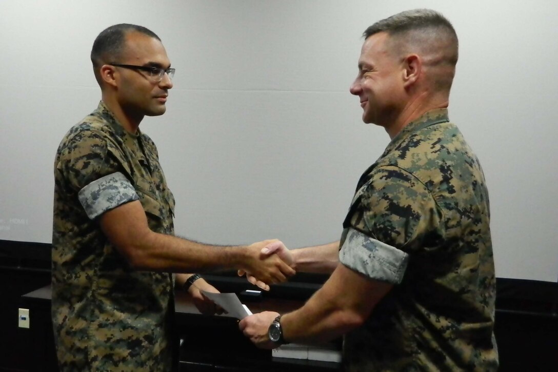 米海兵隊基地キャンプ・コートニー基地司令官のネイション大佐（右）から漢字能力検定合格証書を手渡してもらうディアス伍長（左）。4人の海兵隊員が6月16日（日）に行われた検定試験を受験し、２人の隊員が合格点に達しました。