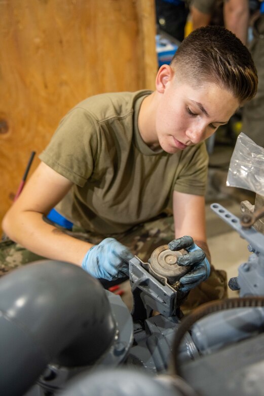 Senior Airman Maeson Bella, 380th Expeditionary Maintenance Squadron aerospace ground equipment journeyman, attaches a solenoid to a diesel engine July 30, 3019, at Al Dhafra Air Base, United Arab Emirates. AGE salvaged parts from an old engine to complete the rebuild and install of a replacement engine for a power cart. (U.S. Air Force photo by Staff Sgt. Chris Thornbury)