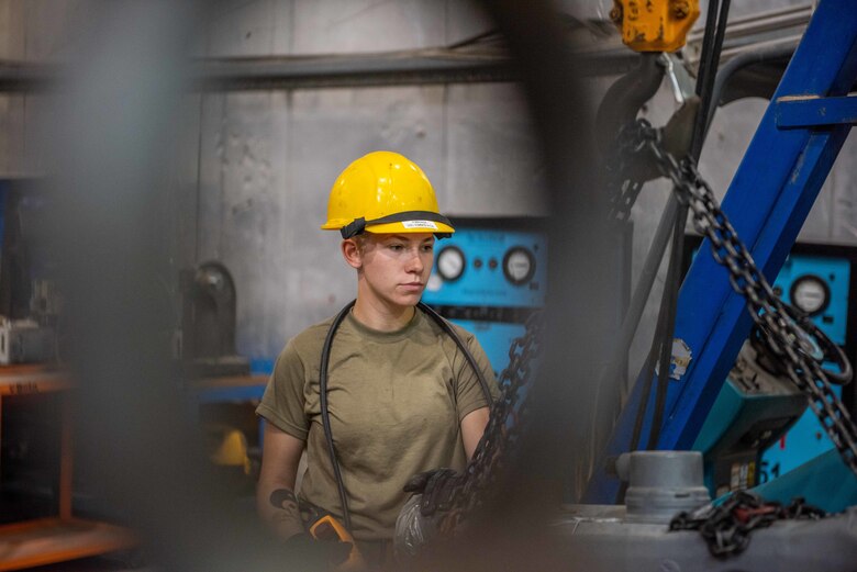 Senior Airman Maeson Bella, 380th Expeditionary Maintenance Squadron aerospace ground equipment journeyman, lifts a diesel engine to place in a -86 power cart July 30, 3019, at Al Dhafra Air Base, United Arab Emirates. Removing the old engine, rebuilding installing the new engine is a three-day process. (U.S. Air Force photo by Staff Sgt. Chris Thornbury)