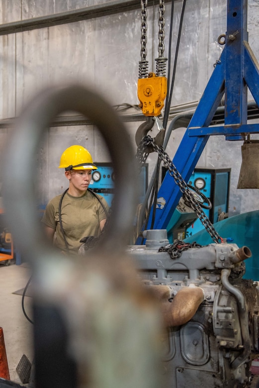 Senior Airman Maeson Bella, 380th Expeditionary Maintenance Squadron aerospace ground equipment journeyman, lifts a diesel engine to place in a -86 power cart July 30, 3019, at Al Dhafra Air Base, United Arab Emirates. Removing the old engine, rebuilding installing the new engine is a three-day process. (U.S. Air Force photo by Staff Sgt. Chris Thornbury)