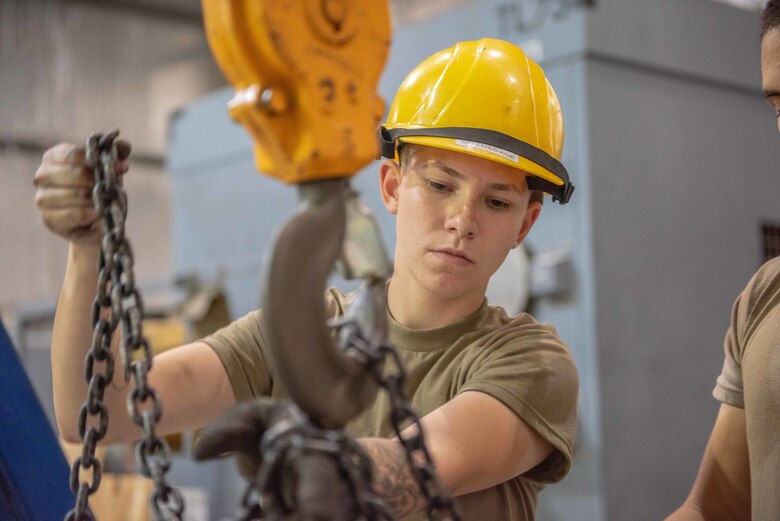 Senior Airman Maeson Bella, 380th Expeditionary Maintenance Squadron aerospace ground equipment journeyman, chains a diesel engine to a lift to place in a -86 power cart July 30, 3019, at Al Dhafra Air Base, United Arab Emirates. Removing the old engine, rebuilding installing the new engine is a three-day process. (U.S. Air Force photo by Staff Sgt. Chris Thornbury)