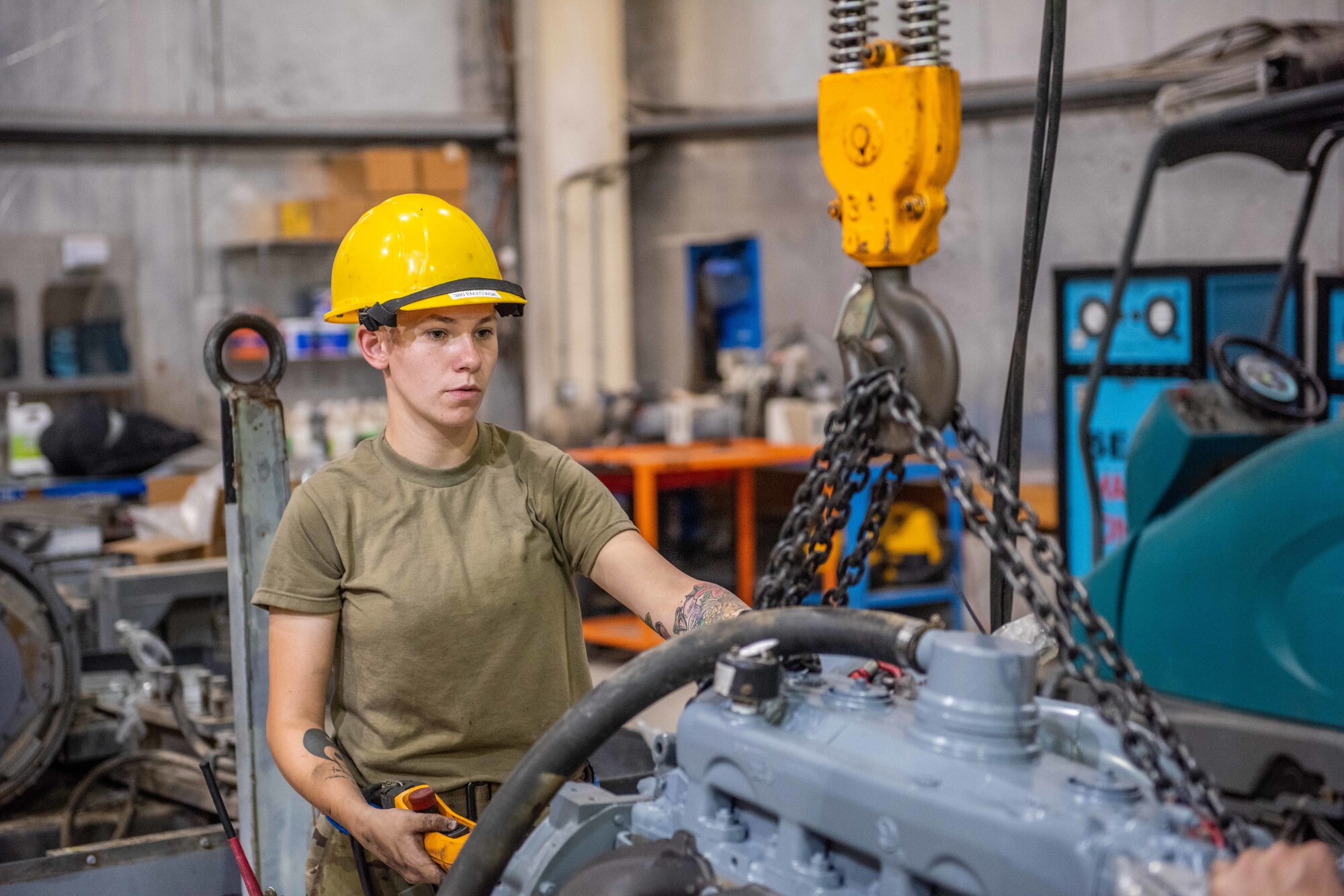 Senior Airman Maeson Bella, 380th Expeditionary Maintenance Squadron aerospace ground equipment journeyman, lifts a diesel engine to place in a -86 power cart July 30, 3019, at Al Dhafra Air Base, United Arab Emirates. Removing the old engine, rebuilding installing the new engine is a three-day process. (U.S. Air Force photo by Staff Sgt. Chris Thornbury)