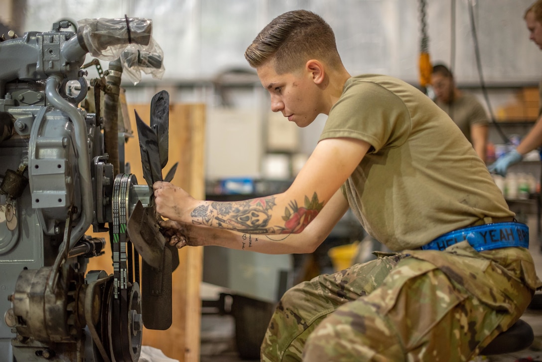 Senior Airman Maeson Bella, 380th Expeditionary Maintenance Squadron aerospace ground equipment journeyman, attaches a fan to a newly rebuilt -86 engine July 30, 3019, at Al Dhafra Air Base, United Arab Emirates. Keeping the unit cool will increase the lifespan in the intense desert summer heat. (U.S. Air Force photo by Staff Sgt. Chris Thornbury)
