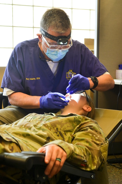 Dr. Roy Delatte, a dentist working with Logistics Health Incorporated (LHI), administers a dental exam during a Soldier Readiness Program (SRP) event sponsored by the 377th Theater Sustainment Command during a scheduled battle assembly at Naval Air Station Joint Reserve Base New Orleans, August 4, 2019.