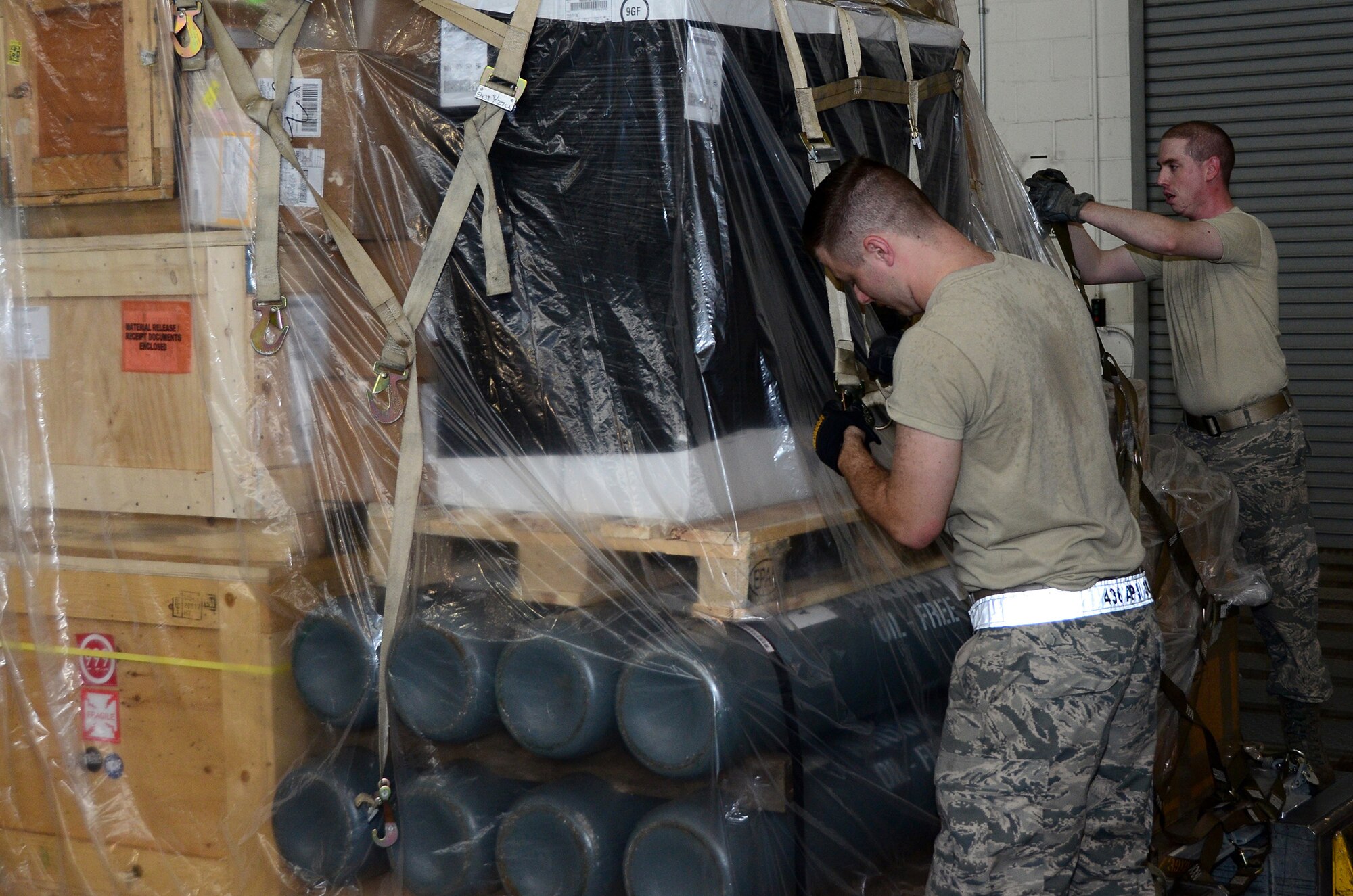 Senior Airman Matthew Ferhman (right), 87th Aerial Port Squadron air transportation journeyman, works with Airman 1st Class Matthew Rahm, 436th Aerial Port Squadron cargo processing specialist, to adjust the top net for a pallet in the cargo processing section at the 436th Aerial Port Squadron, Dover Air Force Base, Delaware, July 19, 2019.