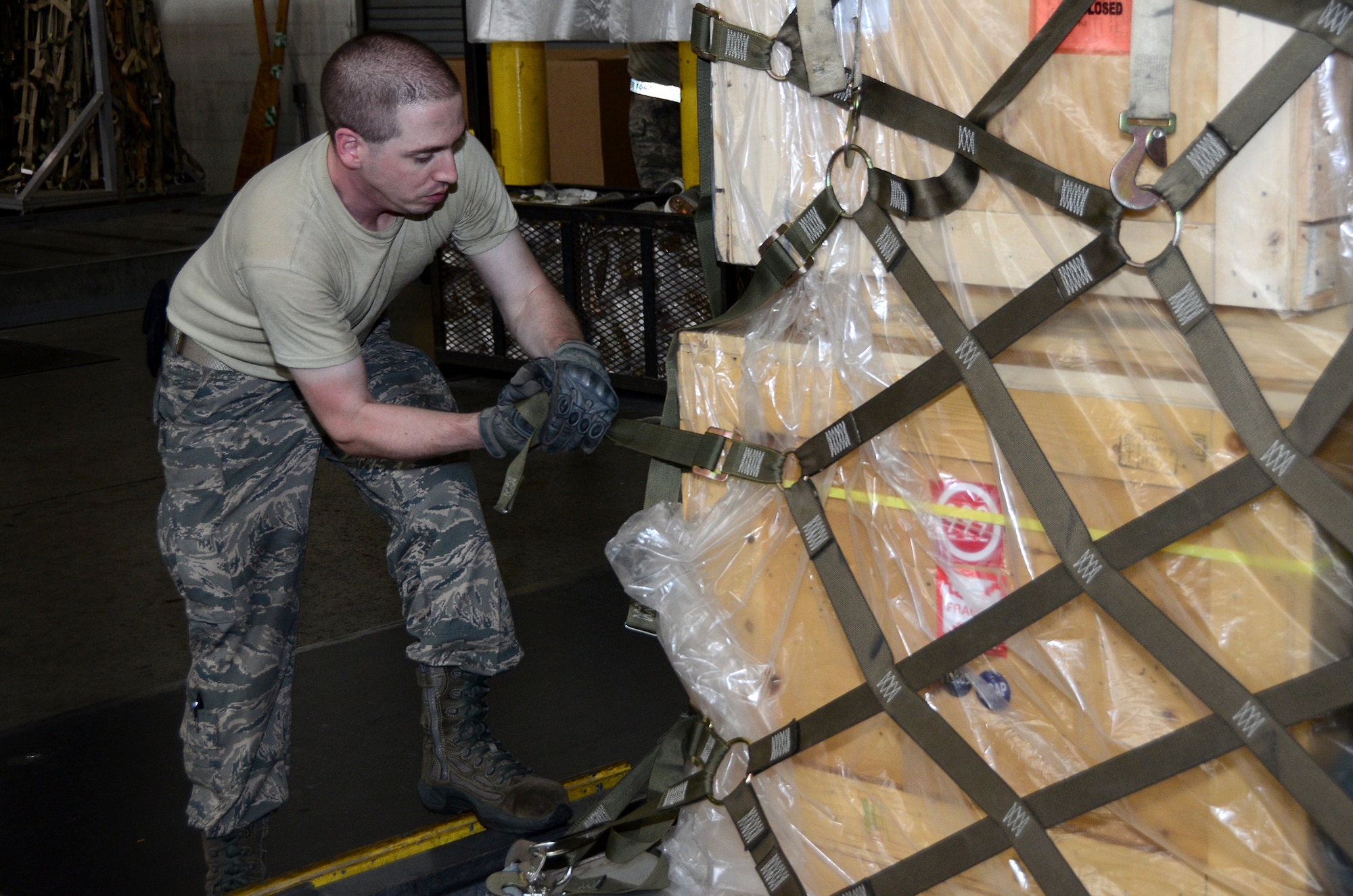 Senior Airman Matthew Ferhman, 87th Aerial Port Squadron air transportation journeyman, tightens a cargo net on a pallet in the cargo processing section at the 436th Aerial Port Squadron, Dover Air Force Base, Delaware, July 19, 2019 during his annual tour training