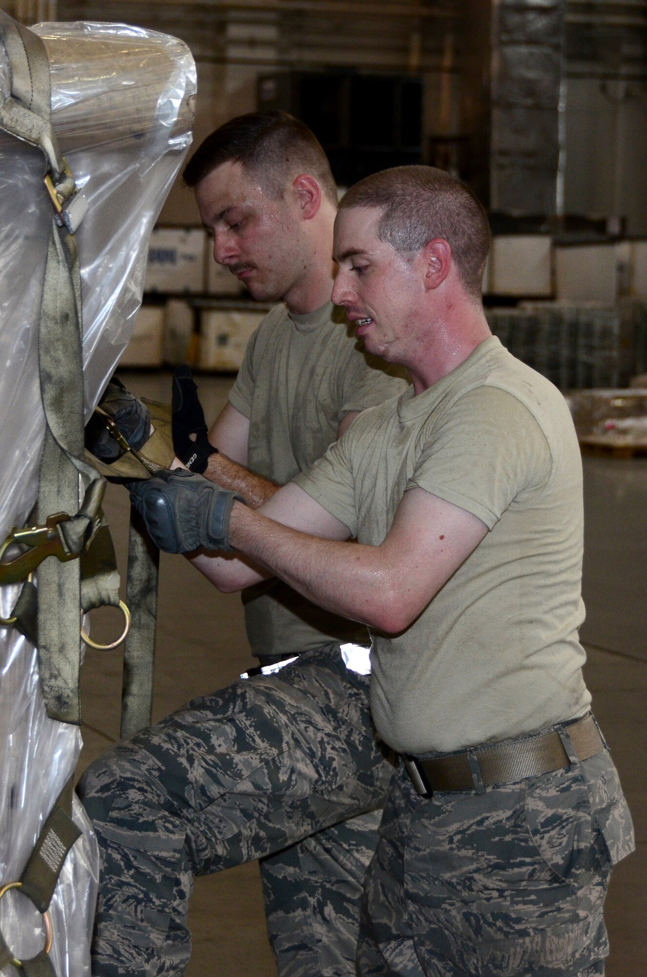 Senior Airman Matthew Ferhman (front), 87th Aerial Port Squadron air transportation journeyman, and Airman 1st Class Matthew Rahm, 436th Aerial Port Squadron cargo processing specialist, adjusts and dress cargo net straps on a newly built pallet at the 436th Aerial Port Squadron, Dover Air Force Base, Delaware, July 19, 2019.