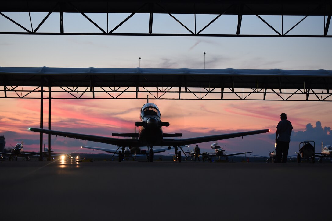 A maintainer guides a T-6 Texan II out of an apron on Aug. 5, 2019 at Columbus Air Force Base, Miss. Student pilots at Columbus have a portion of their training where they fly and navigate at night. (U.S. Air Force photo by Airman Davis Donaldson)