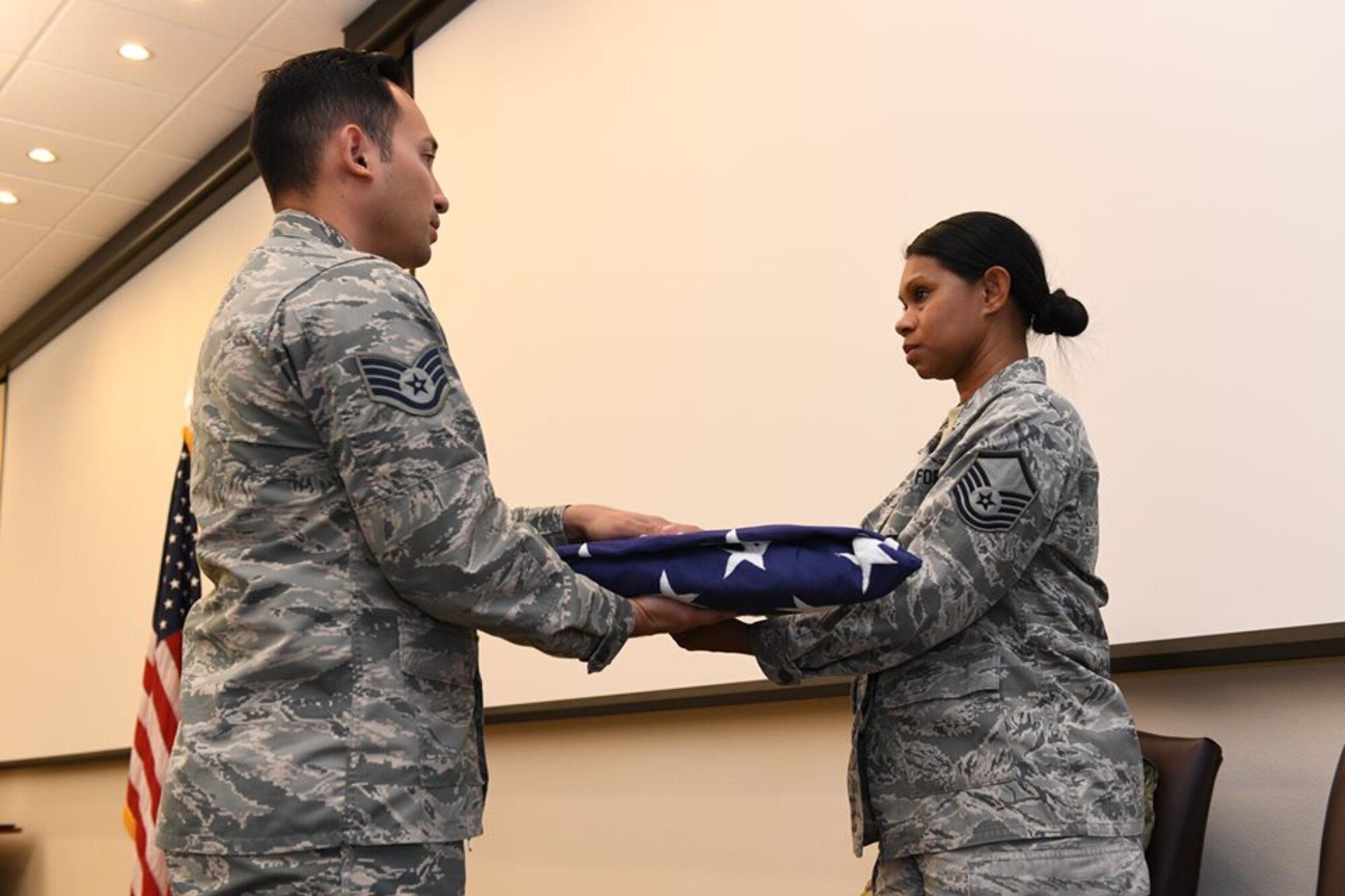 Master Sgt. Myra Heins, the 926th Wing Commander's Support Staff NCOIC, receives a flag from Staff Sgt. Joel Guerrero, a 926th Aerospace Medicine ceremonial team member, during her retirement ceremony Aug. 4 at Nellis Air Force Base, Nevada.