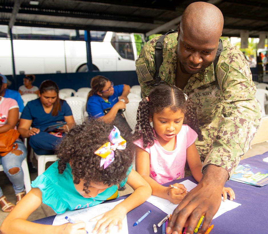 A man draws pictures with children.