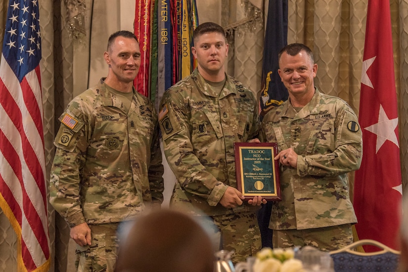 Gen. Paul E. Funk II, commanding general, U.S. Army Training and Doctrine Command, and TRADOC Command Sgt. Maj. Timothy A. Guden, pose for a photo with Sergeant 1st Class Clifford Hammond III, the 2019 Active Duty Noncommissioned Officer Instructor of the Year during the TRADOC Instructor of the Year Awards Ceremony at Fort Eustis, Va., Aug. 7, 2019. The seven awardees were recognized at a ceremony during the TRADOC Commander's Forum.  (U.S. Army photo by Gwyndolynn Giacomo)