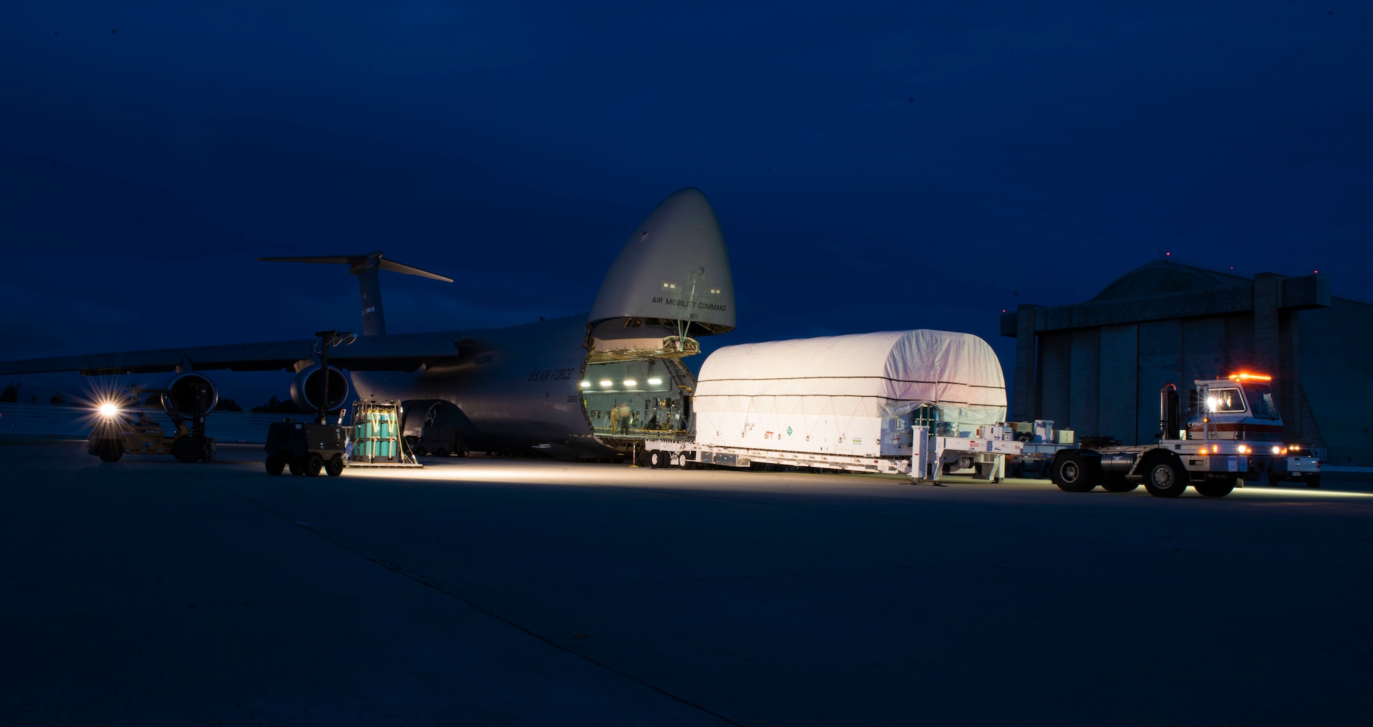 U.S. Air Force Airmen from Team Travis, Space and Missile Systems Center personnel and civilian ground crews load the fifth Advanced Extremely High Frequency communications satellite into a C-5C Galaxy April 19, 2019, at Sunnyvale, California, to transport to Florida. The satellite, was launched into space Aug. 8 and will provide enhanced communications for high-priority military assets.  (U.S. Air Force Photo by Airman 1st Class Jonathan Carnell)