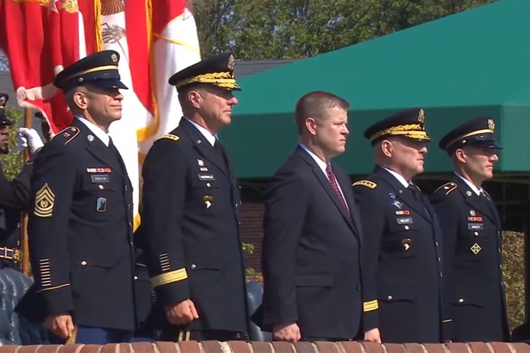 Five men stand shoulder to shoulder during a ceremony.