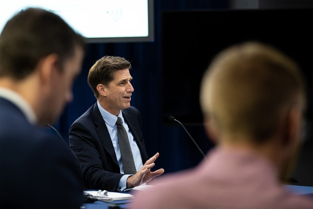 Man speaks while sitting at table.