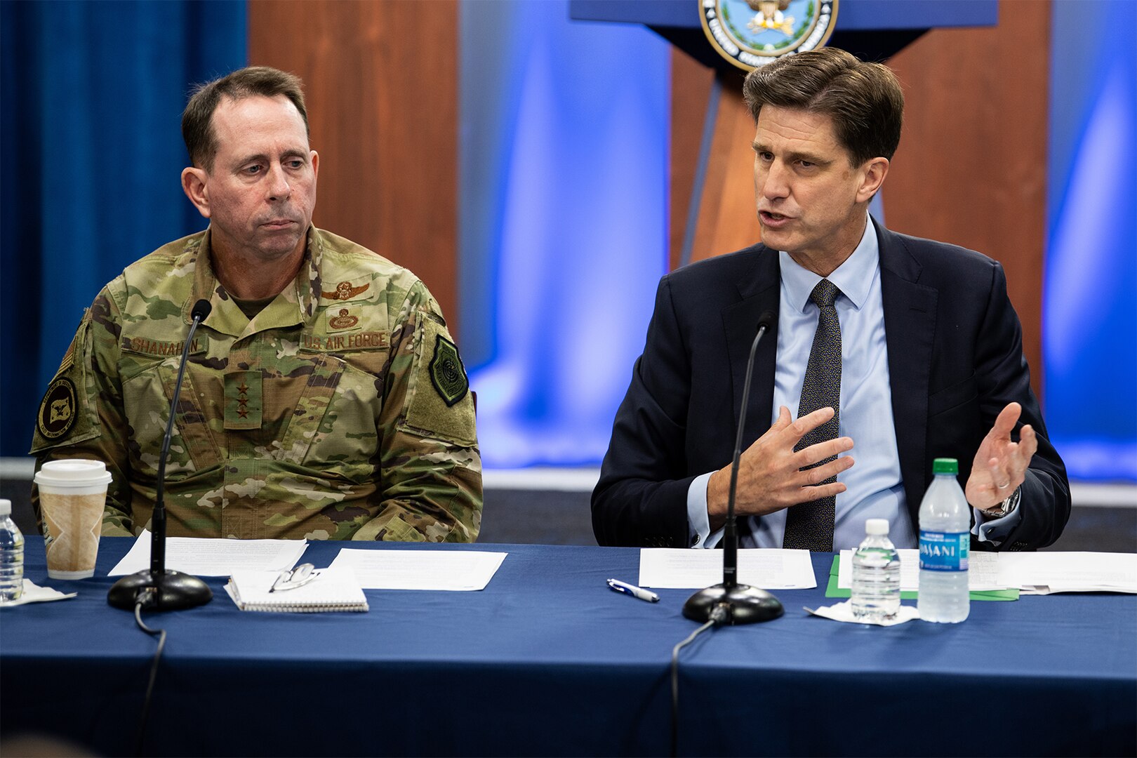 Man speaks while sitting at table.