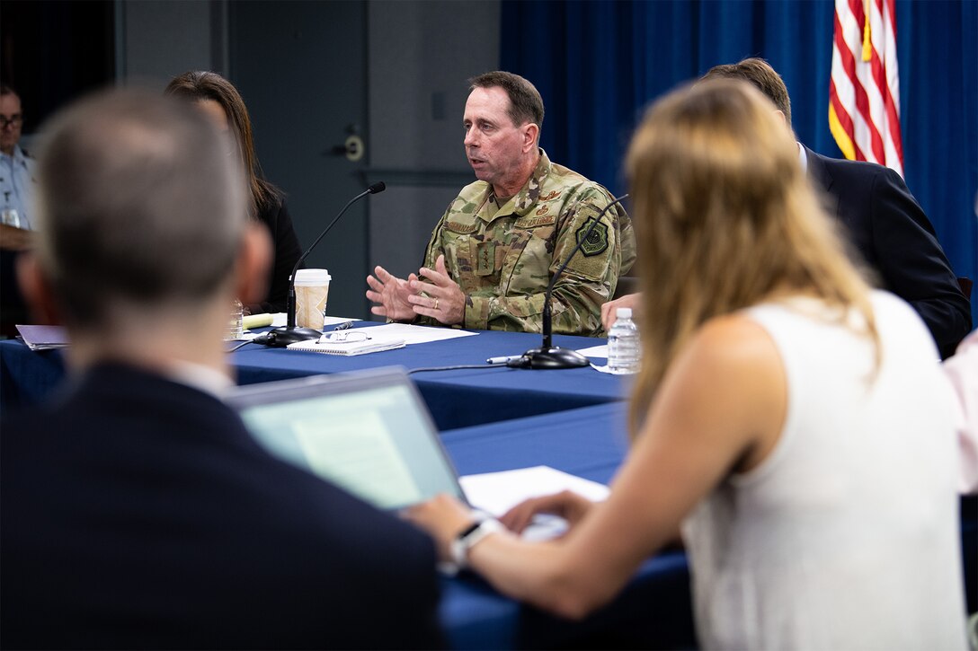 Man speaks while sitting at table.