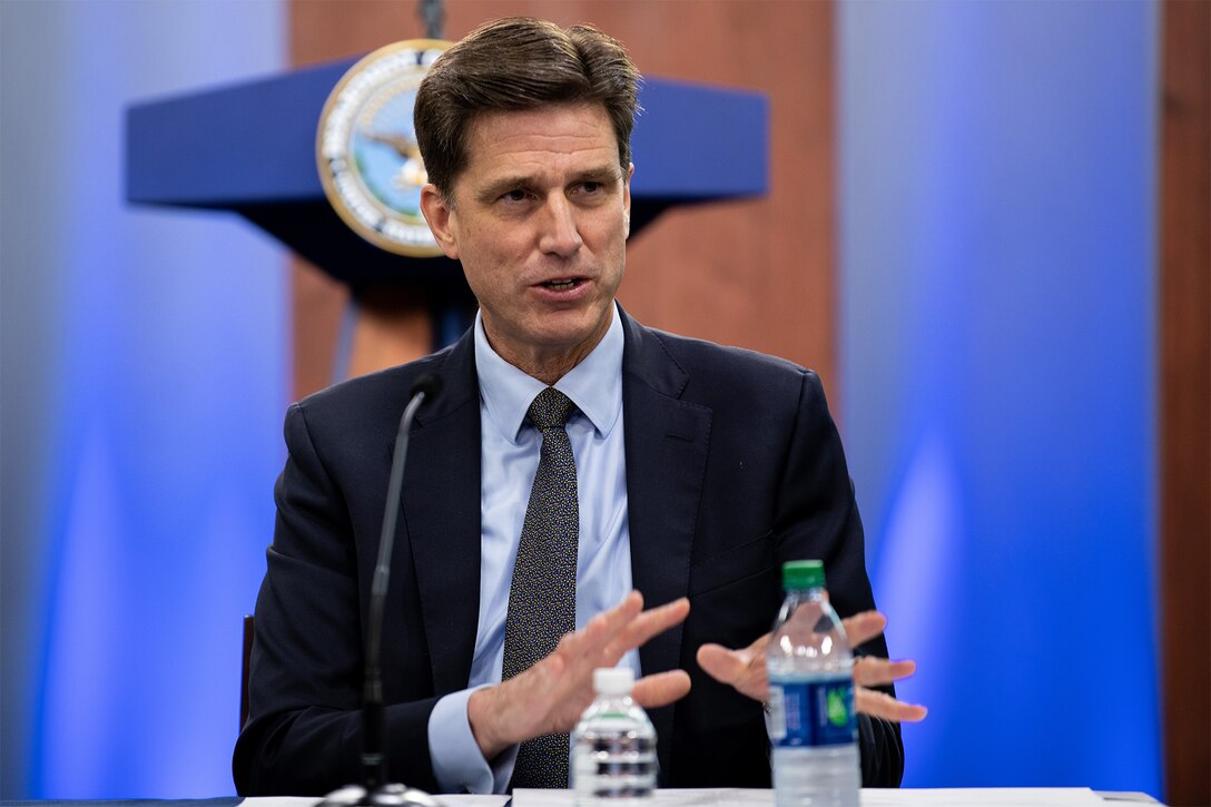 Man speaks while sitting at table.