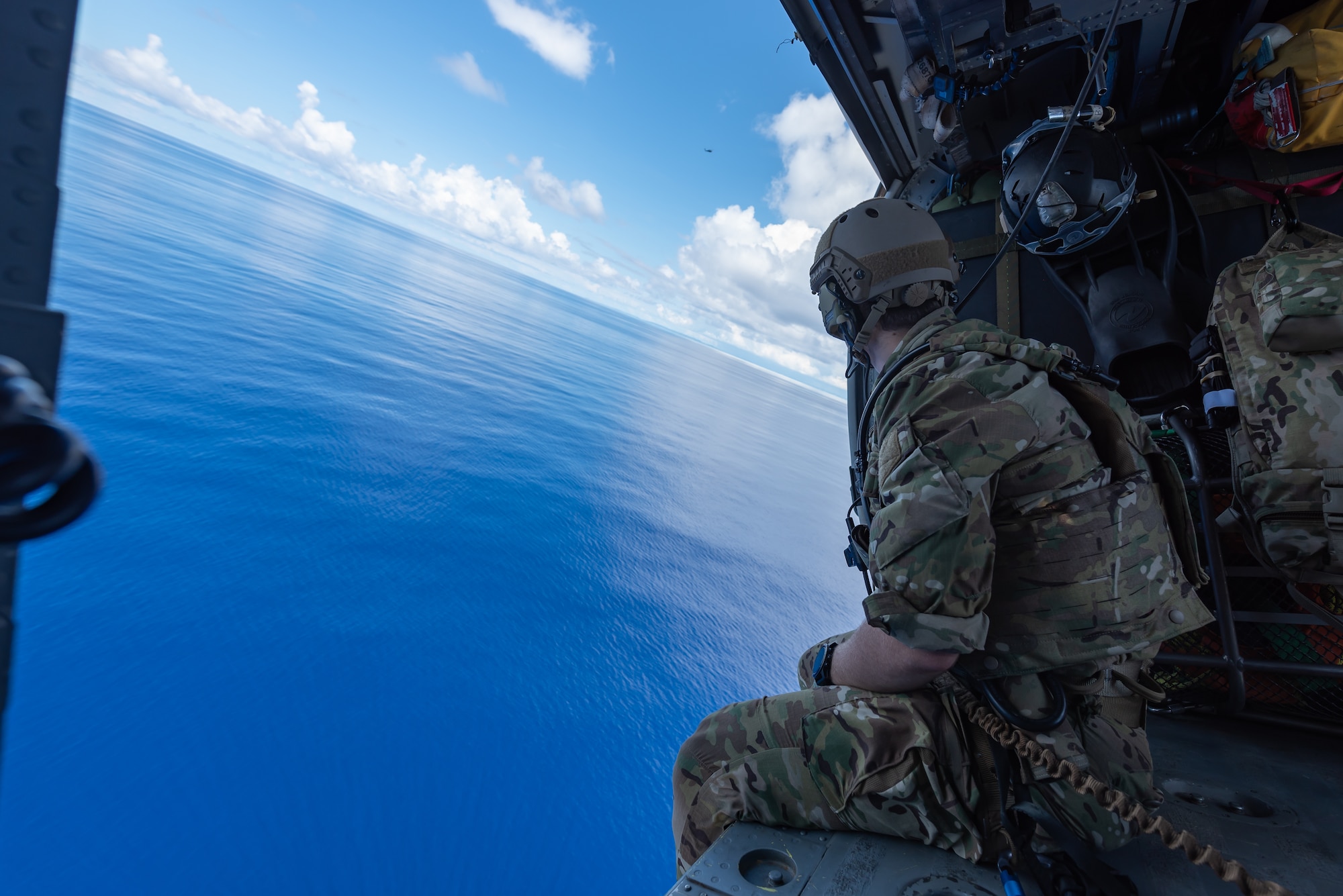 A U.S. Air Force pararescueman assigned to the 31st Rescue Squadron, looks out over the ocean while aboard an HH-60G Pave Hawk, July 26, 2019, out of Kadena Air Base, Japan. The 31st RQS consists of combat rescue officers, pararescue specialists and survival, evasion, resistance and escape specialists who work together to facilitate the return of isolated personnel back to friendly forces. (U.S. Air Force photo by Airman 1st Class Matthew Seefeldt)