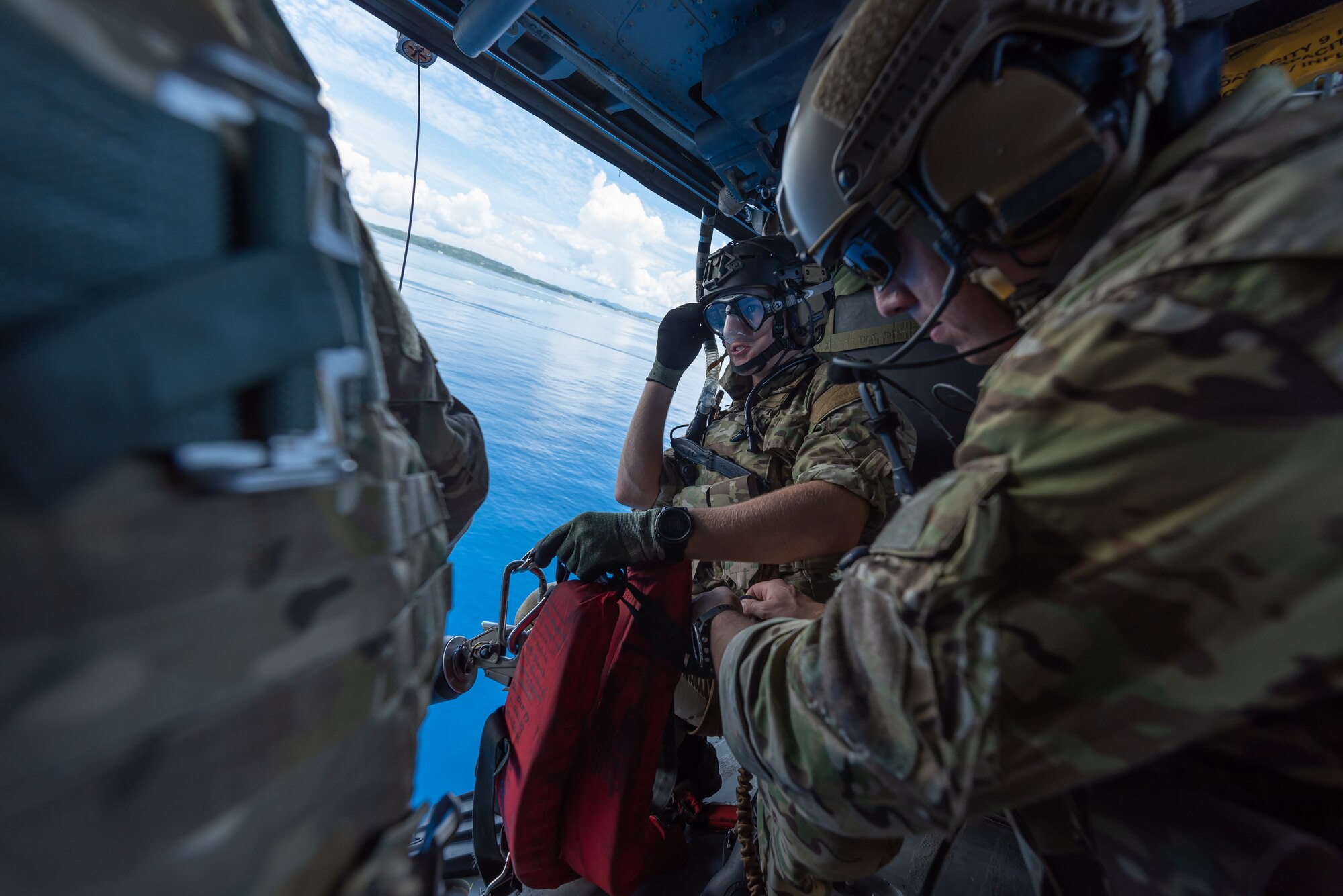 Two U.S. Air Force pararescuemen assigned to the 31st Rescue Squadron, prepare a hoist for a water operation while aboard an HH-60G Pave Hawk, July 26, 2019, out of Kadena Air Base, Japan. The 33rd and 31st RQS both share the same motto, ‘These things we do that others may live.’ (U.S. Air Force photo by Airman 1st Class Matthew Seefeldt)