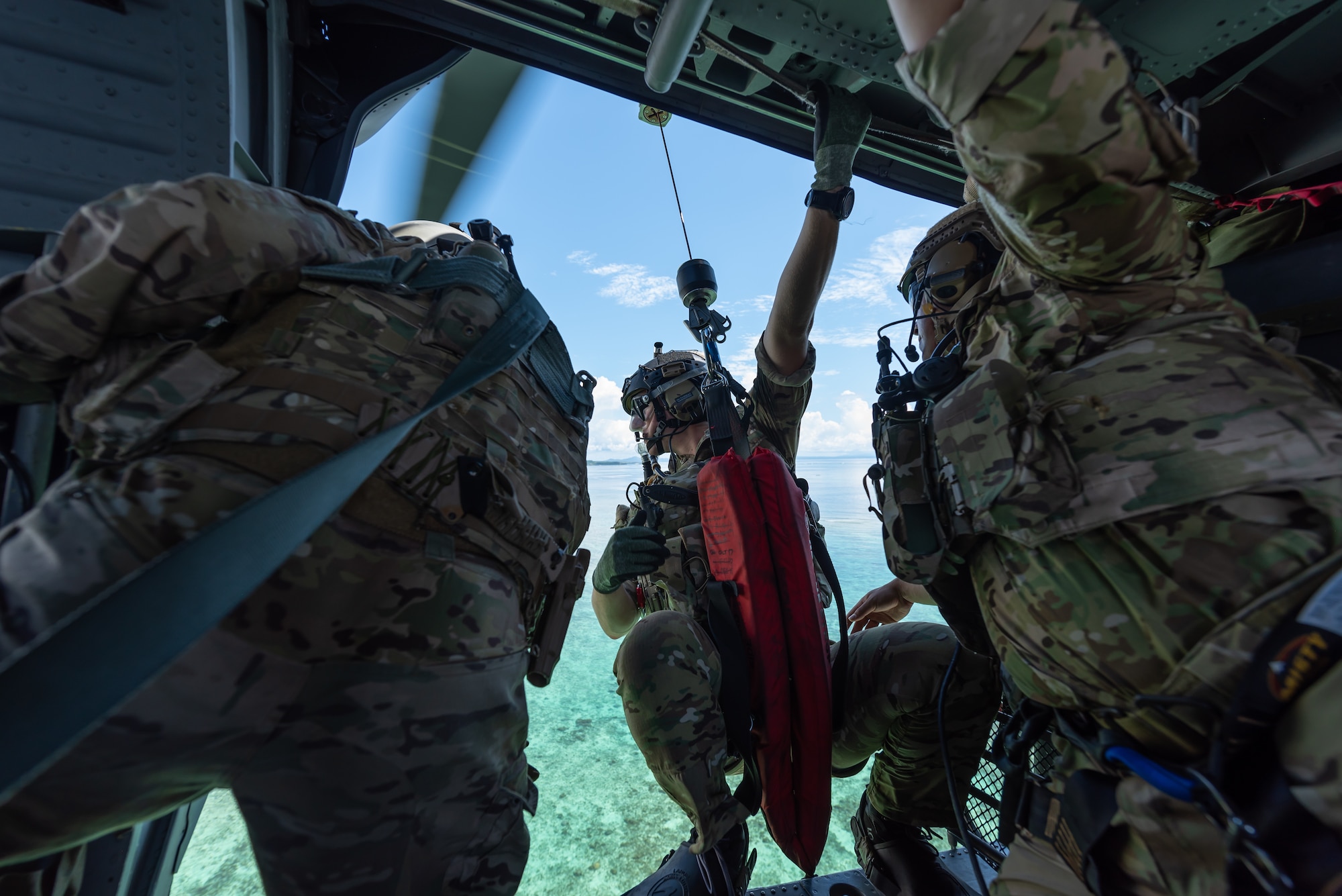 Two U.S. Air Force pararescuemen assigned to the 31st Rescue Squadron, prepare a hoist for a water operation while aboard an HH-60G Pave Hawk, July 26, 2019, out of Kadena Air Base, Japan. Members of the 33rd and 31st Rescue Squadrons from Kadena AB train and work together to provide support for combat rescue and disaster relief. (U.S. Air Force photo by Airman 1st Class Matthew Seefeldt)