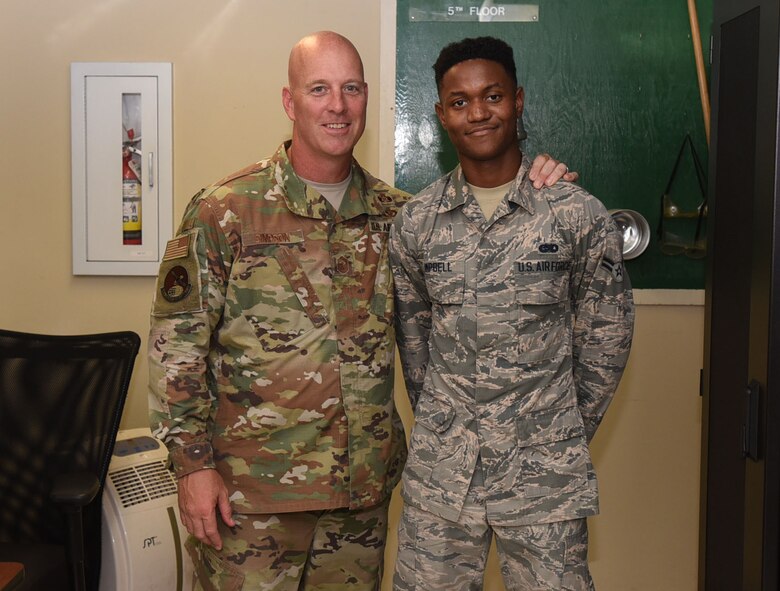 U.S. Air Force Chief Master Sgt. Chris Simpson, 18th Air Force command chief poses with U.S. Air Force Airman 1st Class Leeford Campbell, 305th Operations Support Squadron radar airfields weather system technician, during a tour on Joint Base McGuire-Dix-Lakehurst, N.J., Aug. 1, 2019. During the tour, Simpson coined Campbell in recognition of his hard work and leadership. (U.S. Air Force photo by Airman 1st Class Ariel Owings)