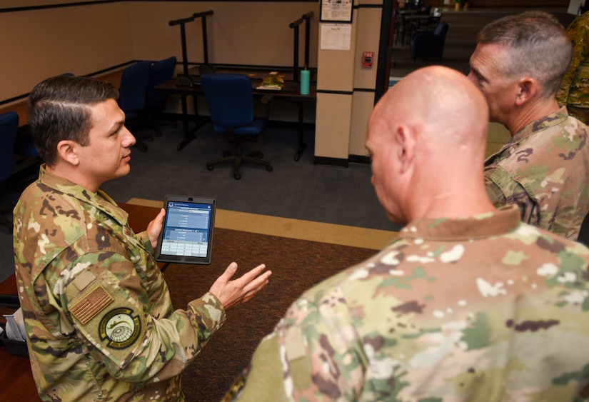 U.S. Air Force Tech. Sgt. Luis Gomez-Duque, 423rd Mobility Training Squadron C-17 Globemaster III apex course director, showcases an app with checklists and guidelines to U.S. Air Force Chief Master Sgt. Chris Simpson, 18th Air Force command chief and U.S. Air Force Chief Master Sgt. Brian Eastman, 305th AMW command chief, during a tour on Joint Base McGuire-Dix-Lakehurst, N.J., Aug. 2, 2019. The app provides information to students and offer a simulation they can use through virtual reality to grasp a better understanding of how it feels to fly an aircraft without physically doing so. (U.S. Air Force photo by Airman 1st Class Ariel Owings)