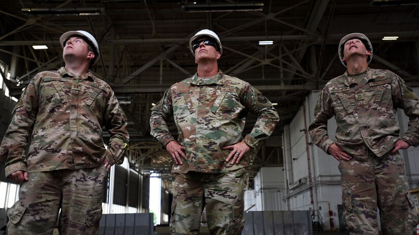 U.S. Air Force Capt. Christopher Logue, 305th Air Mobility Wing KC-46 Pegasus civil engineering program manager, U.S. Air Force Chief Master Sgt. Chris Simpson, 18th Air Force command chief and U.S. Air Force Chief Master Sgt. Brian Eastman, 305th AMW command chief, look inside of a hangar during a tour on Joint Base McGuire-Dix-Lakehurst, N.J., Aug. 2, 2019. The hangar known as “Big Beige” is the largest in-use hangar on the McGuire annex of Joint Base MDL. (U.S. Air Force photo by Airman 1st Class Ariel Owings)