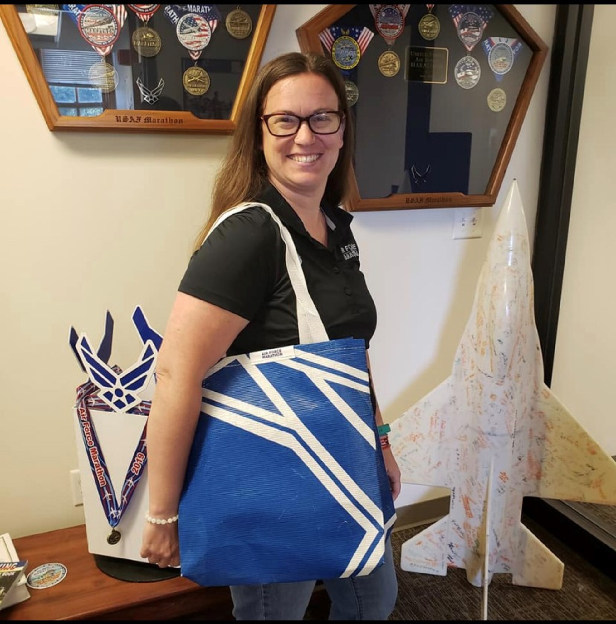 Rachael McKinney, Air Force Marathon events coordinator and Green Program lead, models the tote bag that will be given away to the “Fly Fight Win” challenge participants. The bag was made from sections of a former finish line chute at a previous race. (Courtesy photo)