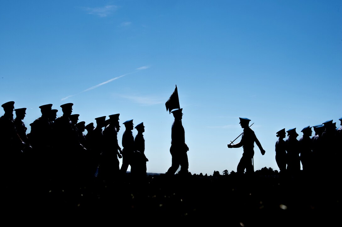 Air Force cadets are silhouetted against the sky during a parade.