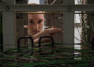 U.S. Air Force Senior Airman Dorian Stacy, 423rd Communications Squadron network operations technician, inspects wires for cleanliness and corrosion at RAF Alconbury, England, August 8, 2019. Stacy is in charge of securing network operations and ensuring proper access and permissions are in place at RAF Alconbury and RAF Molesworth. (U.S. Air Force photo by Airman 1st Class Jennifer Zima)