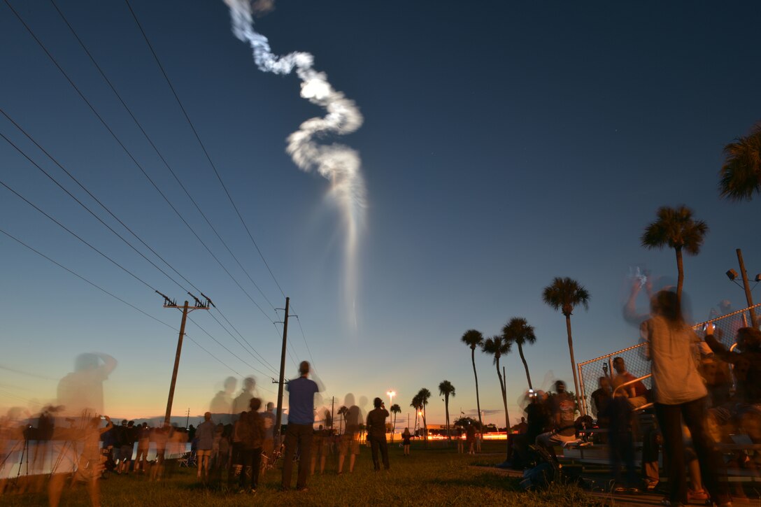 People watch an Atlas V rocket launch.