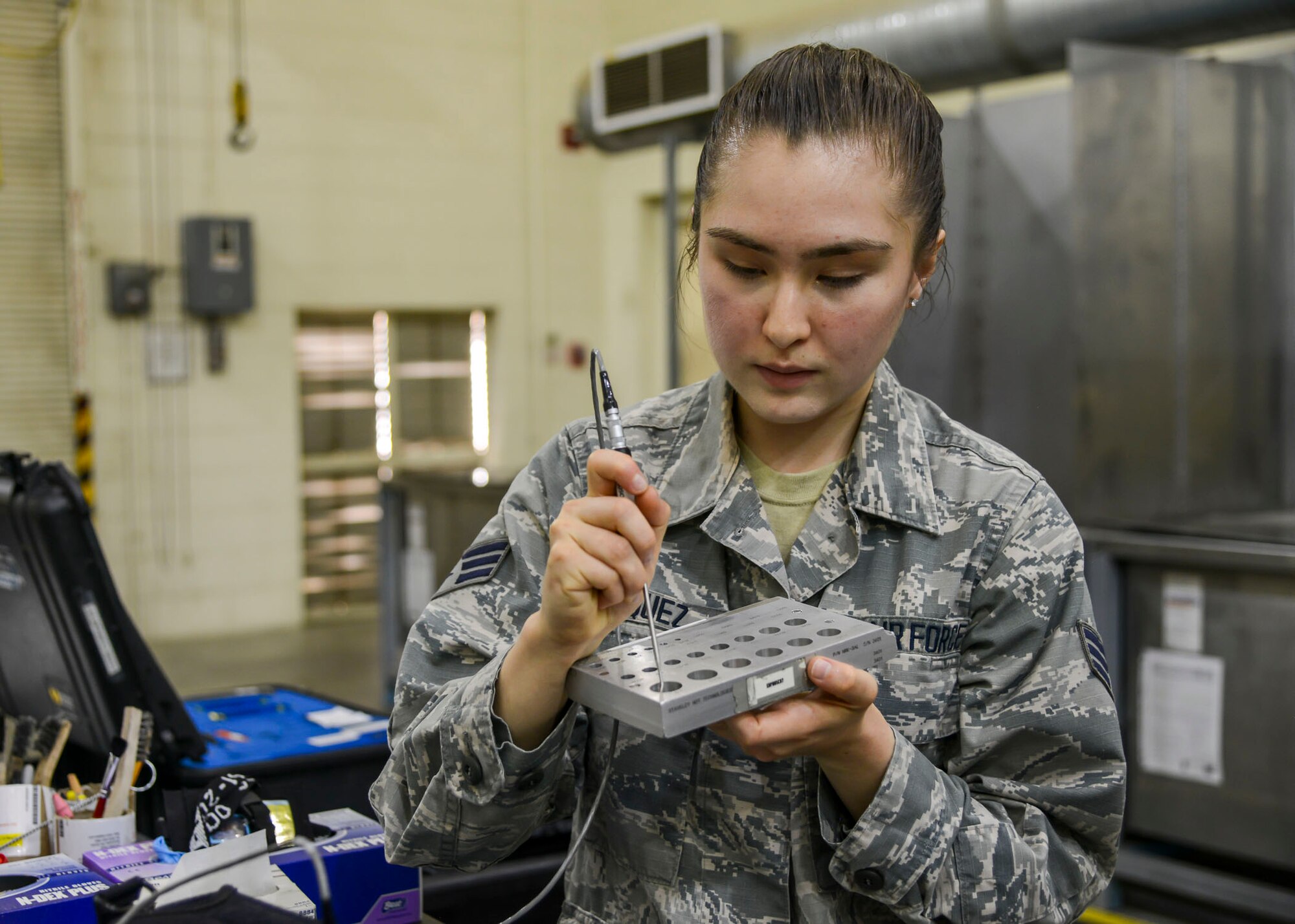 Senior Airman Aliyah Vasquez, 412th MXS, Non-Destructive Inspection Section, demonstrates a scanning tool used to identify cracks in air plane parts. (U.S. Air Force photo by Giancarlo Casem)