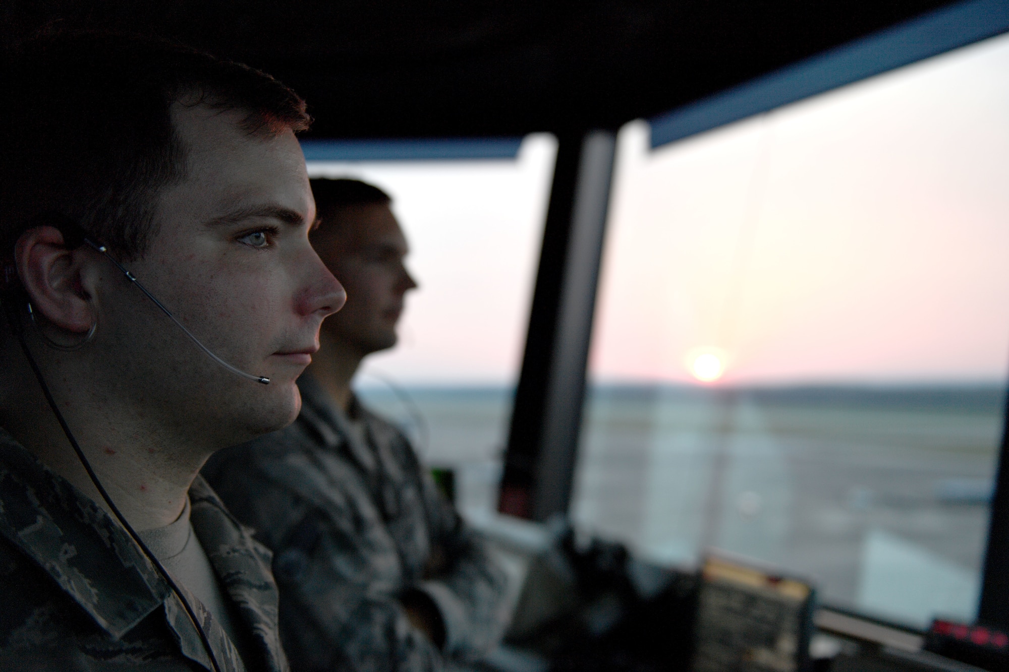 Two men stare out a window.