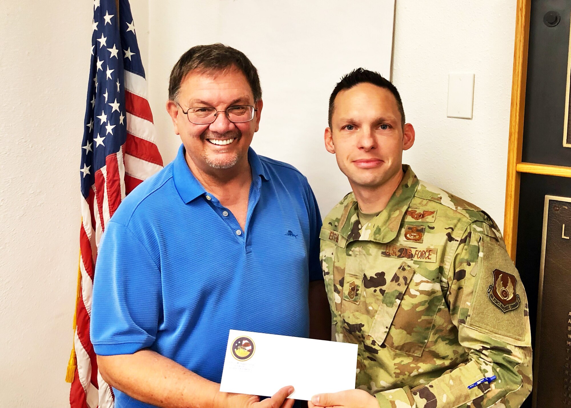 Edwards Air Force Base Civilian-Military Support Group president Al Hoffman presents a $300 check to Command Chief Master Sgt. Ian EISHEN, the 412th Test Wing Command Chief, at the Lancaster Chamber of Commerce in Lancaster, California, Aug. 8. The donation was made on behalf of local singer, "Rat Pack" Ricky Medlin. The money will be used to support the Edwards AFB Youth Center. (U.S. Air Force photo by Danny Bazzell)